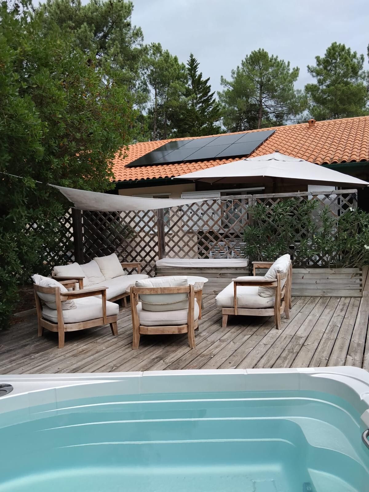 Terrasse en bois avec salon de jardin, modules photovoltaïques sur le toit de tuiles canal