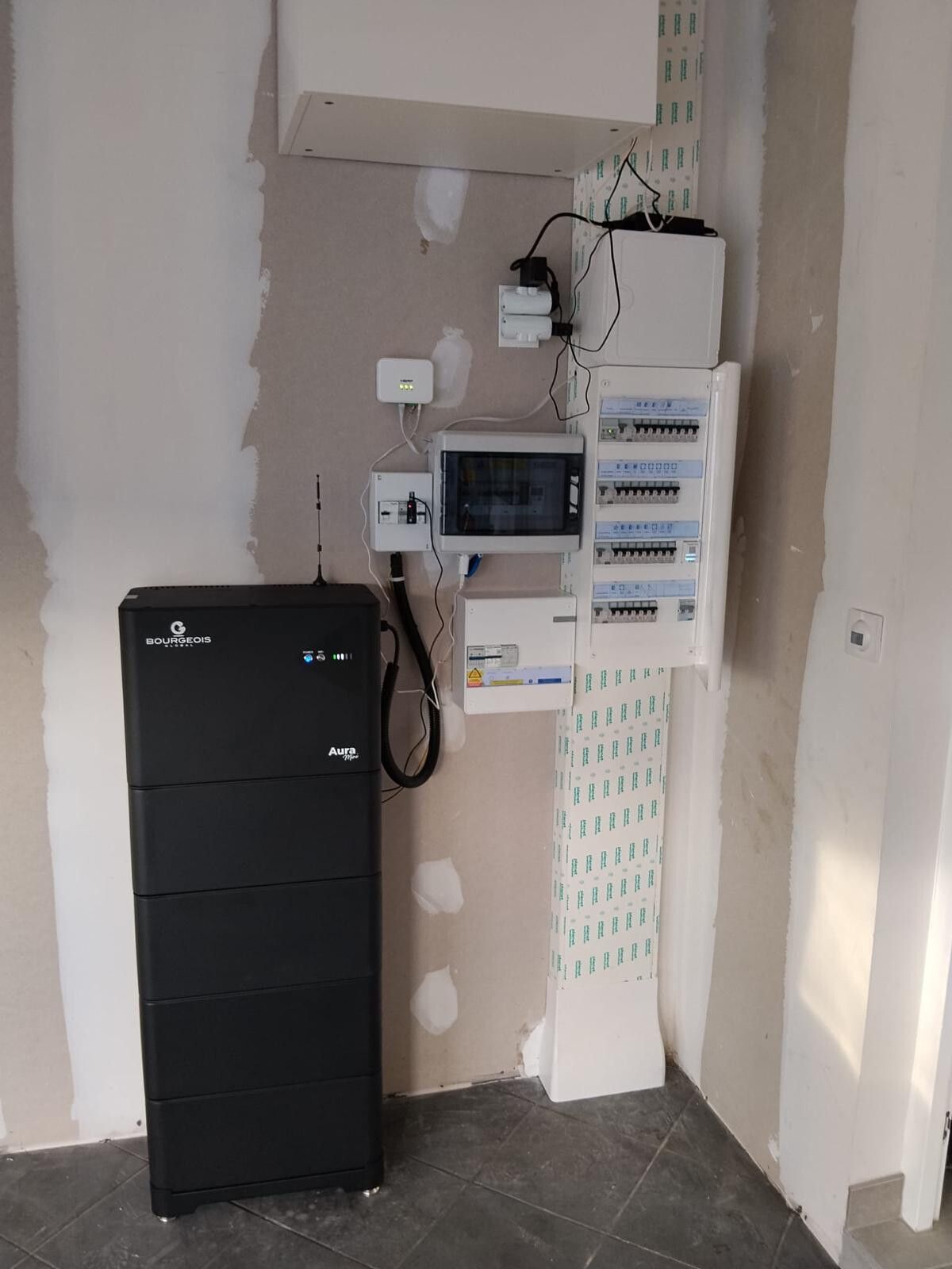 Batterie domestique posée au sol contre un mur, sous le tableau électrique