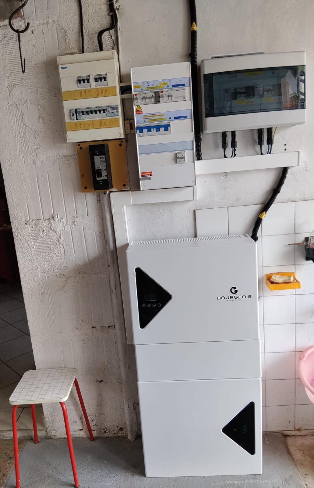 Onduleur blanc avec son écran de contrôle, posé au mur d'un garage