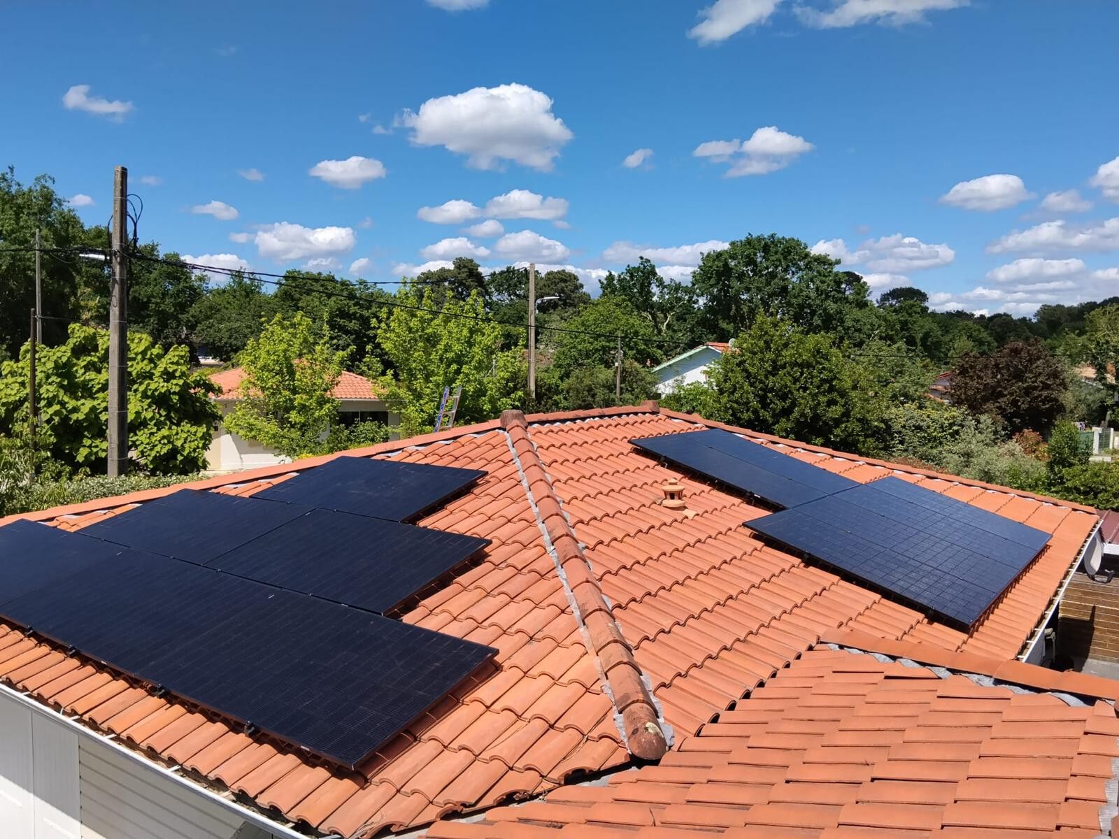 Modules photovoltaïques sur un toit de tuiles canal, arbres et ciel bleu